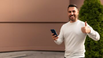 un homme est content de son smartphone et lève le pouce
