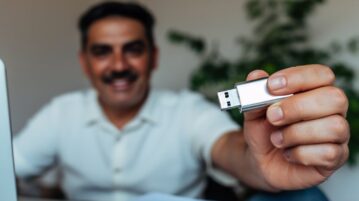 un homme devant son ordinateur montre une cle usb