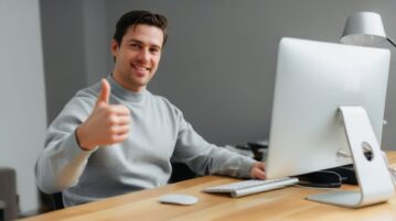 un homme satisfait devant son ordinateur lève le pouce