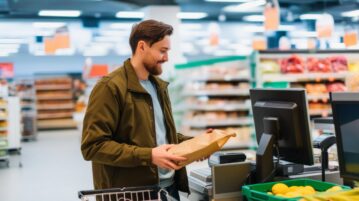 un homme paye ses courses à la caisse d'un magasin avec le sourire